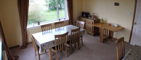 A dining area with a table and chairs, a kitchen area with a counter and appliances, and a window with curtains.