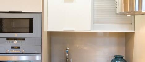 A modern kitchen with stainless steel appliances, a blue sink, and a decorative glass vase.