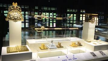 Une exposition dans un musée présentant divers objets, notamment un grand et somptueux couvre-chef, une épée et plusieurs petites sculptures.