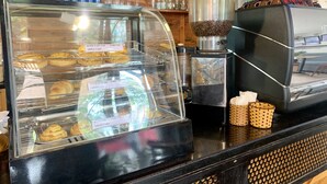 A bakery display case with pastries and a coffee machine. - Nice Hue Hotel (Hue)