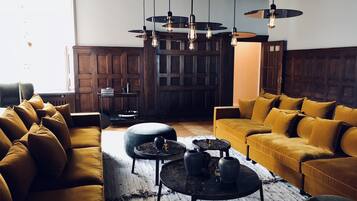 A modern living room with a large window, wooden paneling, and a yellow sofa set.