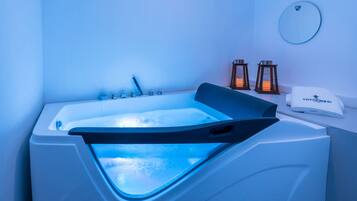 Bathroom features a large bathtub, round mirror, and wall-mounted lanterns.