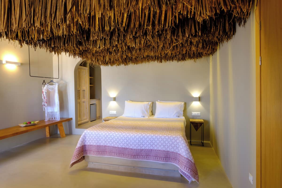 A bedroom with a bed, bedside tables, a bench, and a wardrobe.