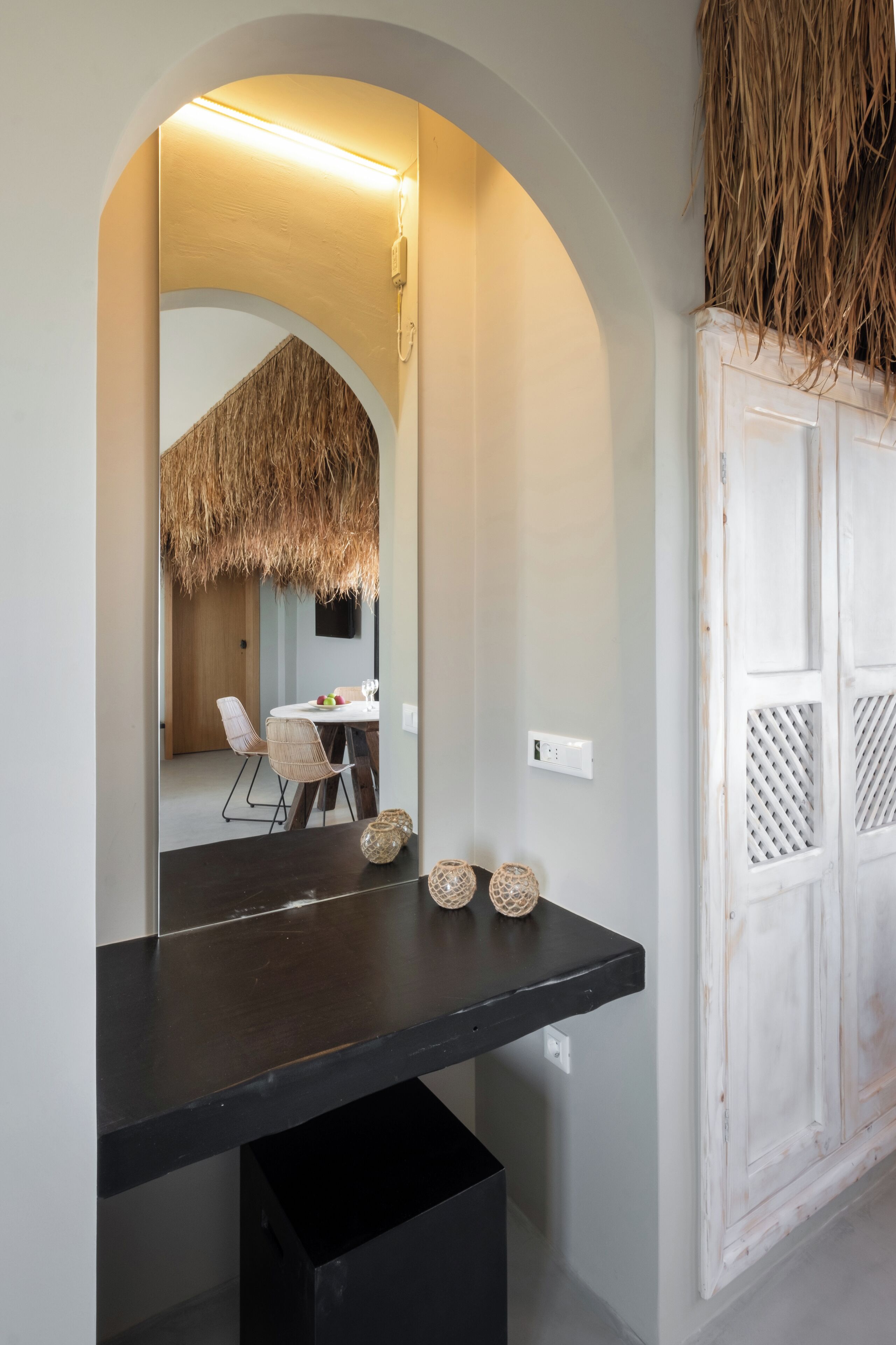 A modern interior with a dark countertop, a white door with a lattice design, and a thatched ceiling in the background.