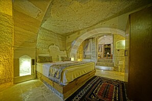 A stone-walled bedroom with a bed, a rug, and a window. - Cappa Cave Hotel (Nevsehir)