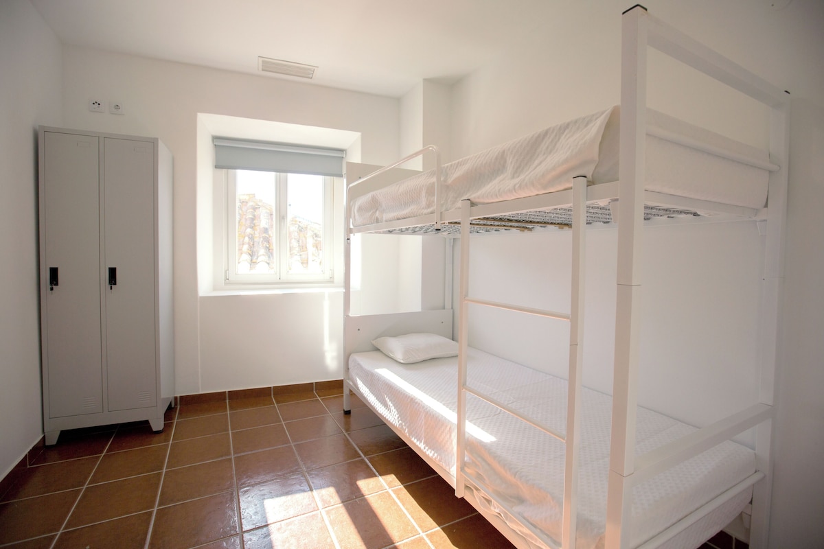 Dormitorio con literas, ventana, armario y suelo de baldosas.