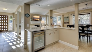 A kitchen with a built-in oven, a sink, and a dining area with a table and chairs. - 102 Beachwalk – Your Coastal Retreat Just Moments from the Shore! (Hilton Head Island)
