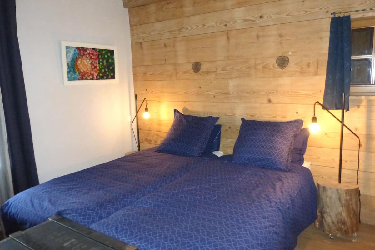 A wooden-paneled room with a bed, two bedside lamps, and a small table.