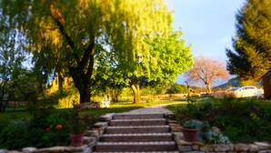 A stone staircase leading to a garden with a large tree, a white car parked nearby, and a stone wall. - Chambres D'Hôtes Bered Vuillemin (Baume-les-Dames)