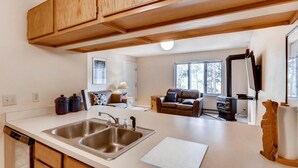 Una cocina moderna con un lavamanos doble, armarios de madera, un comedor con mesa y sillas, un sofá y una chimenea.