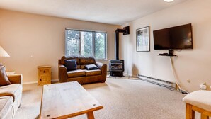 Una sala de estar con sofá, mesa, televisor y chimenea.
