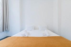 A single bed with white linens, a brown throw blanket, and two pillows. - HI Lisboa – Pousada de Juventude - Hostel (Lisbon)