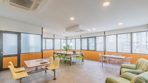 A modern conference room with large windows, a table with chairs, and a sofa. - HI Lisboa – Pousada de Juventude - Hostel (Lisbon)
