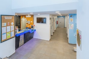 A reception area with a blue counter, a bulletin board with messages, and a reception sign. - HI Lisboa – Pousada de Juventude - Hostel (Lisbon)