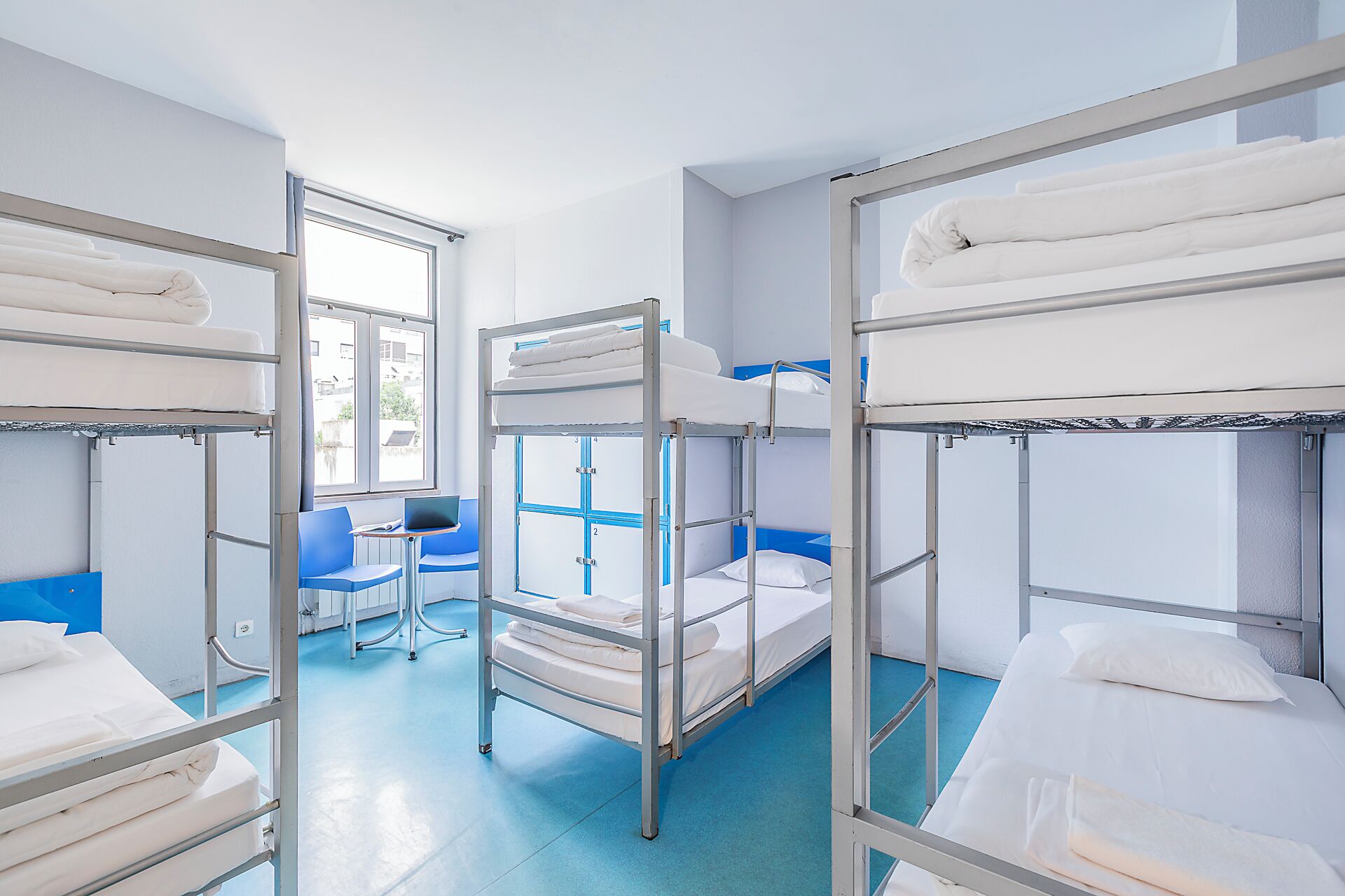 Een studentenkamer met stapelbedden, een bureau en een stoel.