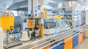 A commercial kitchen with food dispensers, a coffee machine, and a clock on the wall. - HI Lisboa – Pousada de Juventude - Hostel (Lisbon)