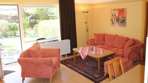 A living room with a sofa, armchair, and a small table with a checkered tablecloth. - Apartmenthaus Padua (Büsum)
