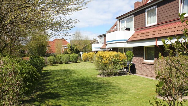 A residential house with a well-maintained lawn, a brick exterior, and a small garden area. - Apartmenthaus Padua (Büsum)