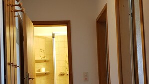 A narrow hallway with a blue mat leading to a bathroom. - Apartmenthaus Padua (Büsum)