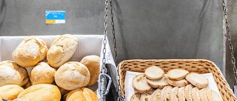 Two baskets of bread, one with whole loaves and the other with sliced bread, hanging from chains.