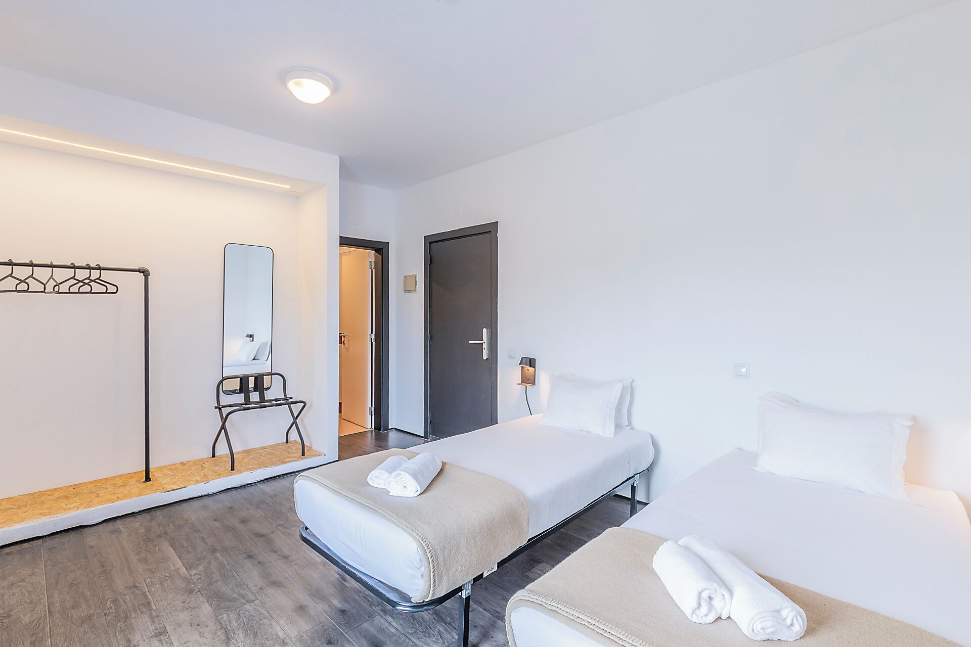 Ein Hotelzimmer mit zwei Betten, einem Spiegel, einem Kleiderschrank und einer kleinen Sitzecke.