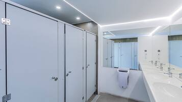 A modern bathroom with lockers, a large mirror, and multiple sinks.