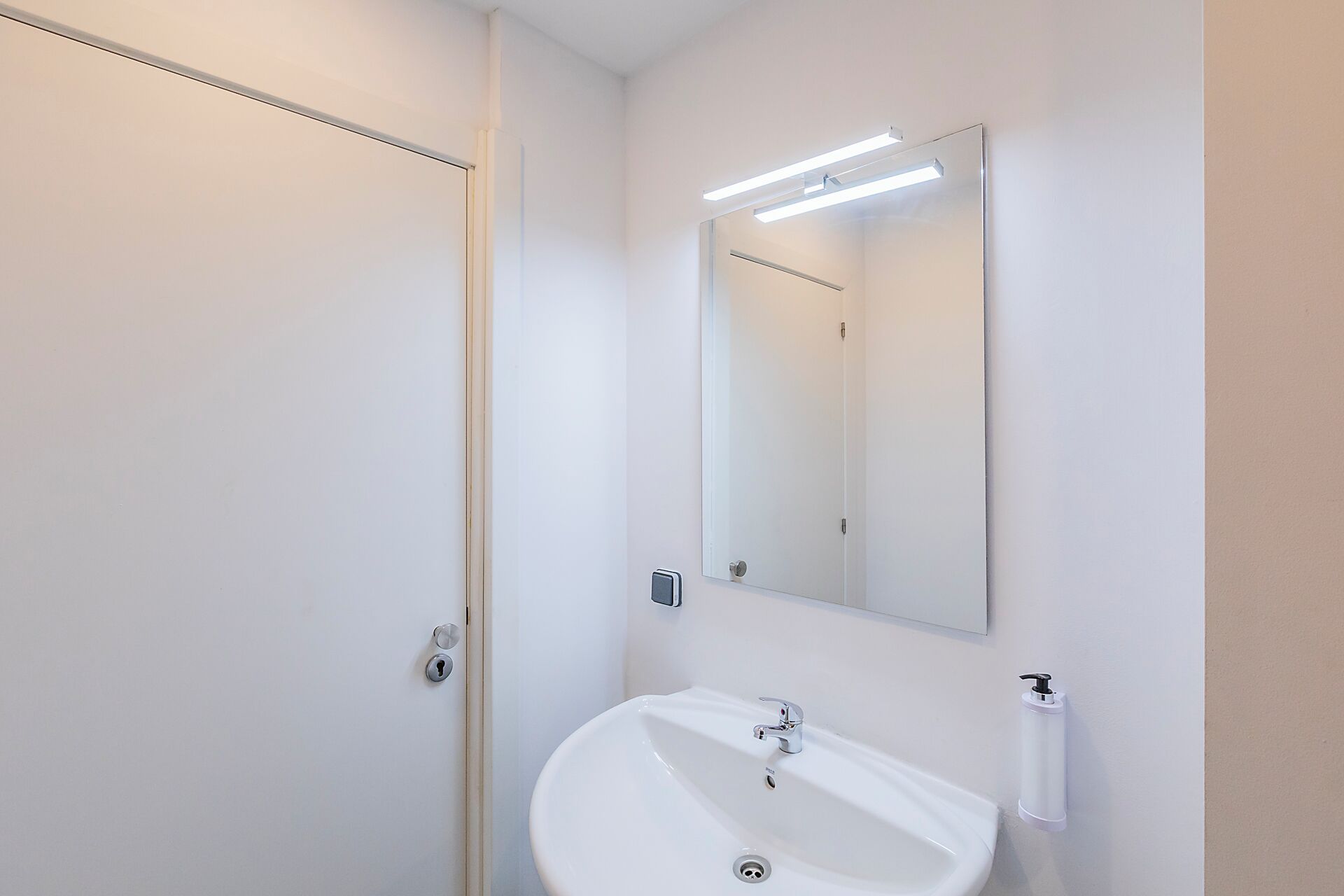 Un baño con un lavamanos blanco, un espejo y un inodoro.