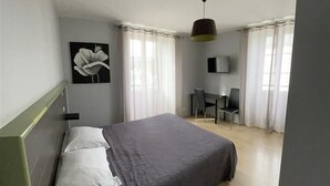Een slaapkamer met een bed, een bureau en een televisie.
