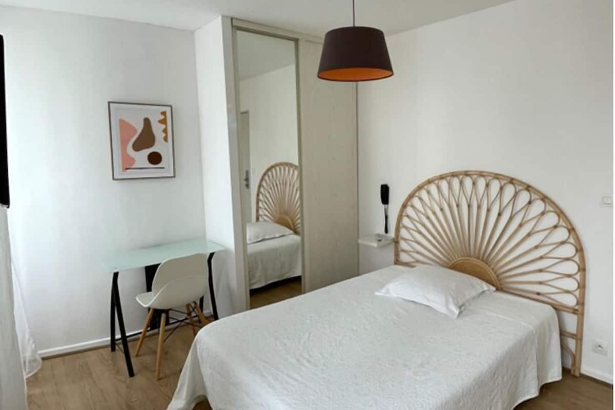 Une chambre à coucher avec un lit, un bureau, une chaise et une lampe suspendue.