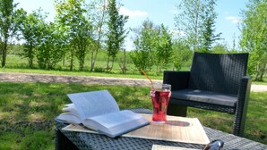 A wicker table with an open book, a glass of drink, and sunglasses. - La Ferme de Marpalu (La Ferte-Saint-Cyr)