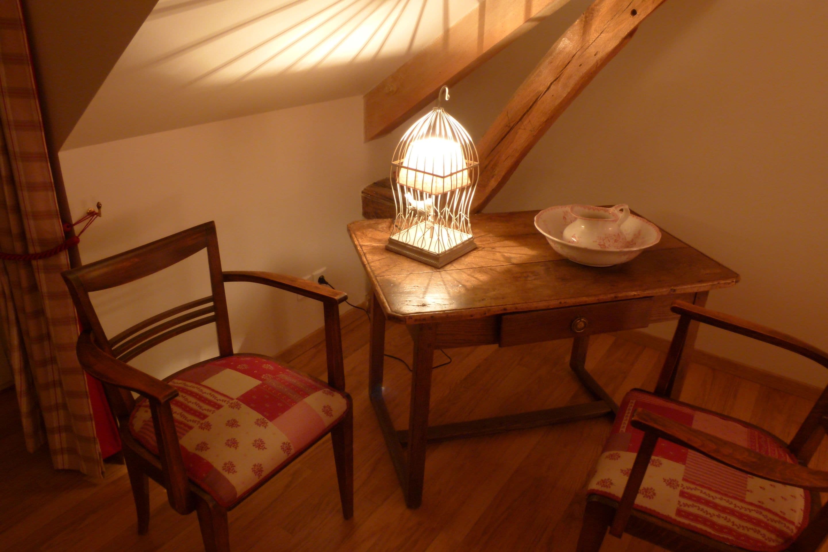 Een gezellige kamer met een houten tafel, twee stoelen, een decoratieve lamp en een schaal.