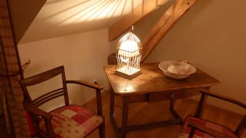 Een gezellige kamer met een houten tafel, twee stoelen, een decoratieve lamp en een schaal.