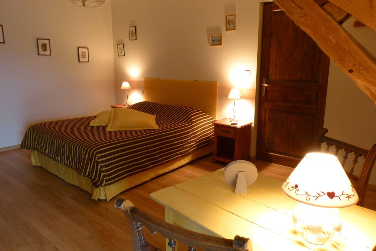 A bedroom with a bed, bedside tables, a lamp, and a wooden chair.