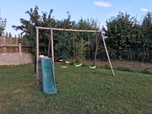 Un parque infantil con un tobogán y columpios.