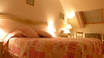 A bedroom with a bed, pillows, a nightstand, a lamp, a chair, and a desk.
