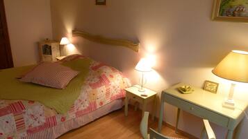 A bedroom with a bed, bedside lamps, a desk, and a chair.