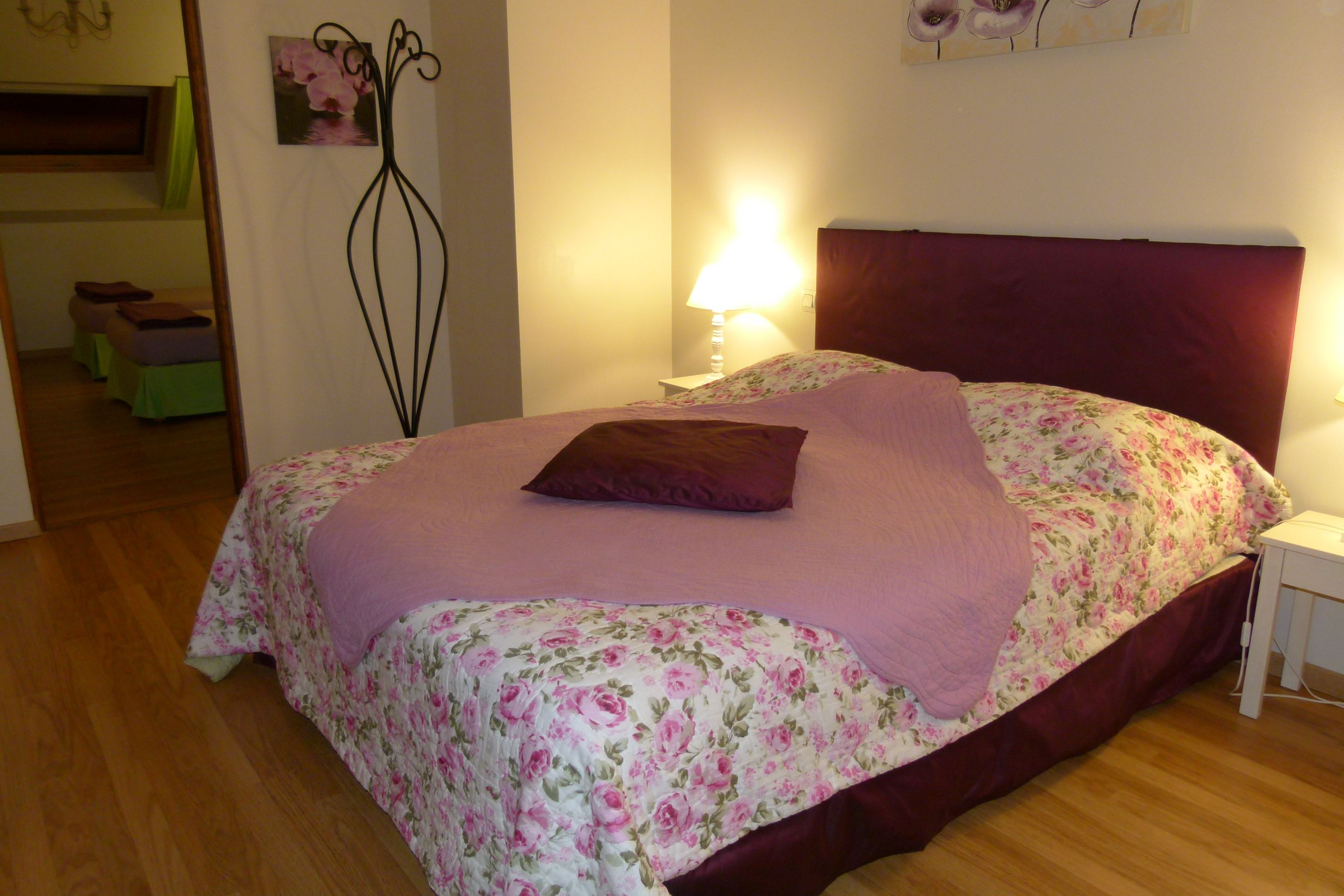 Une chambre à coucher avec un lit, une lampe de chevet et une couvre-lit à motifs floraux.