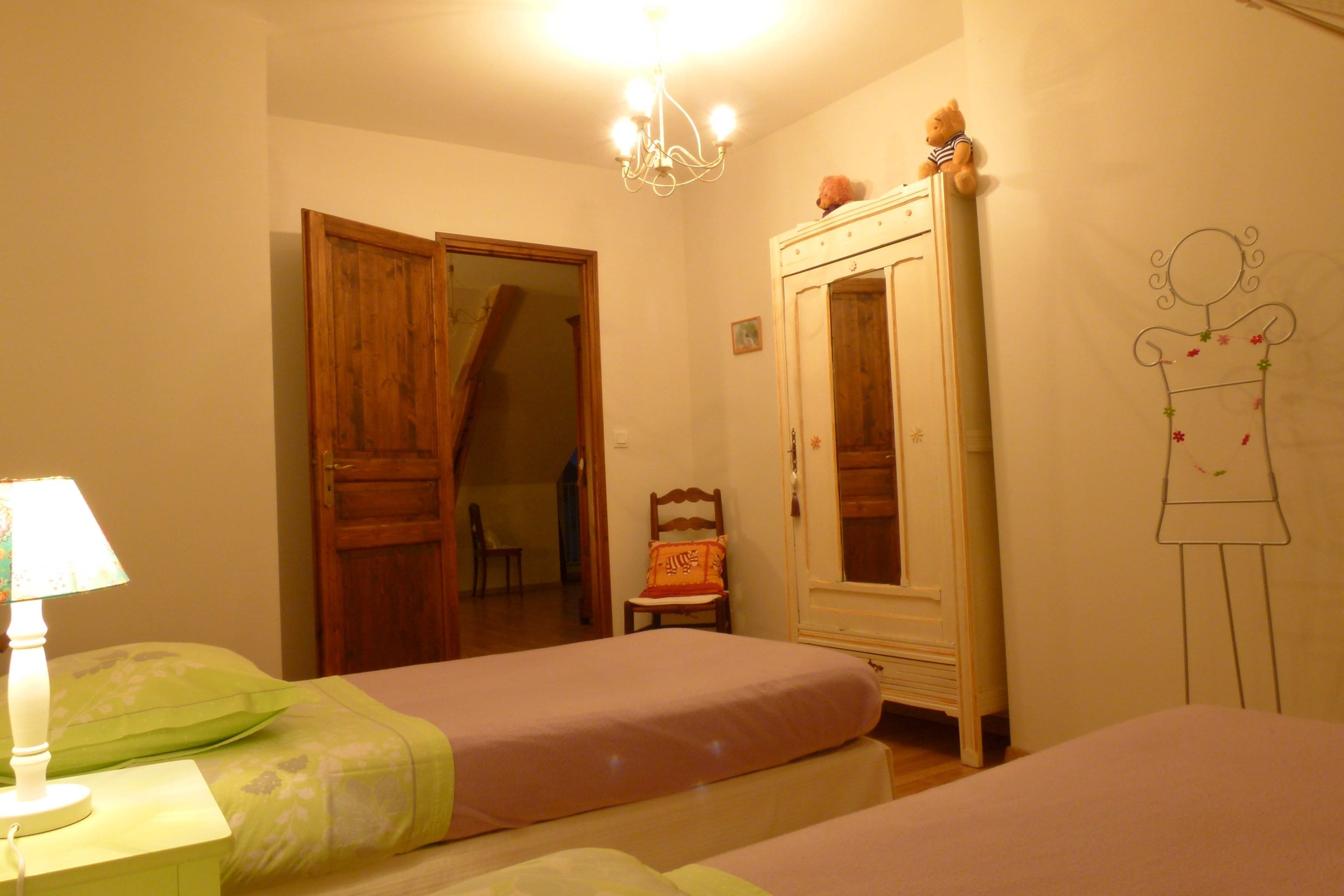 Un dormitorio con dos camas, un armario de madera, una silla y un adorno en la pared.