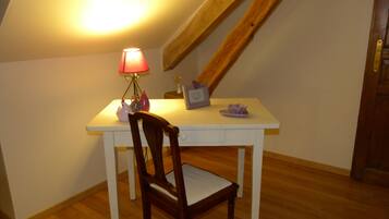 A small, white desk with a chair, a lamp, and a few decorative items.