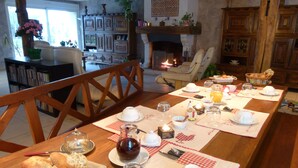 A dining area with a long wooden table set for breakfast, including bread, eggs, and beverages. - La Ferme de Marpalu (La Ferte-Saint-Cyr)
