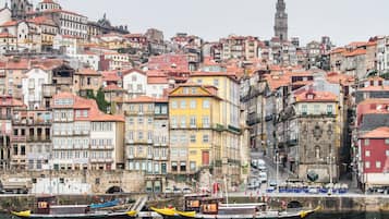 Un paisaje urbano histórico con edificios coloridos, una imponente torre del reloj y un río con barcos.
