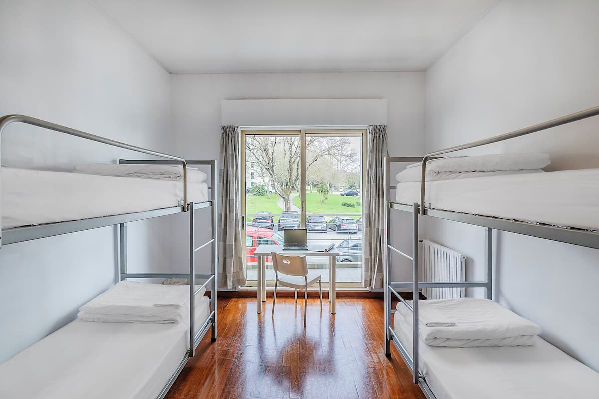 Une chambre avec deux lits superposés, une chaise et une vue sur un parking.