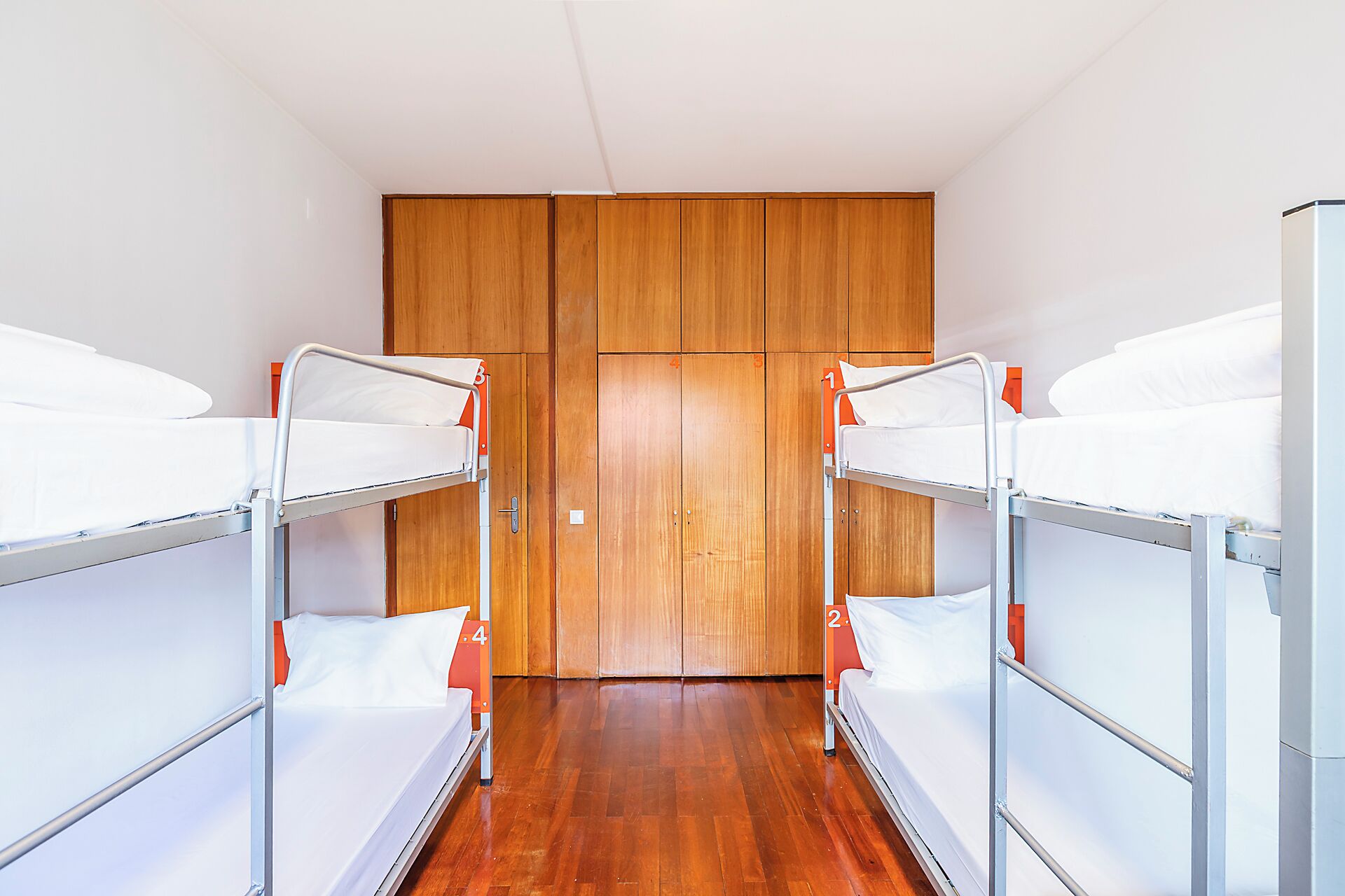 Una habitación con literas, armario de madera y una puerta.
