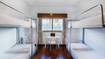 Een slaapkamer met stapelbedden, een bureau en een stoel.