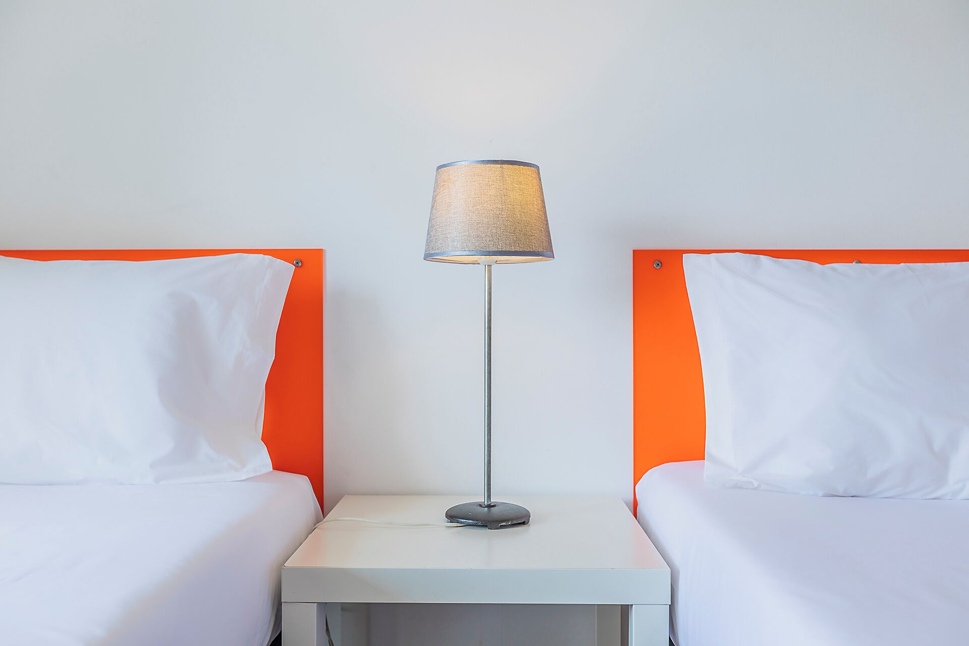 Ein Hotelzimmer mit zwei Betten, einem Nachttisch und einer Lampe.