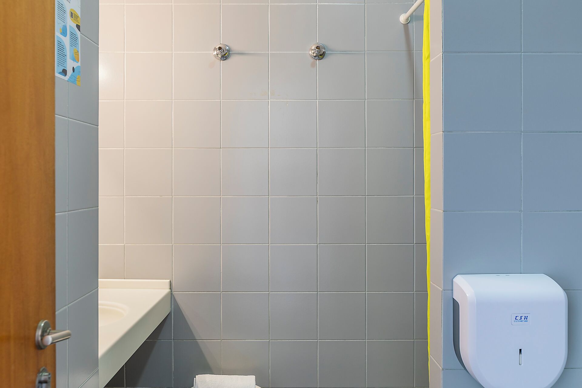 Une salle de bain équipée d’une douche, d’un sèche-mains et d’un porte-serviettes.