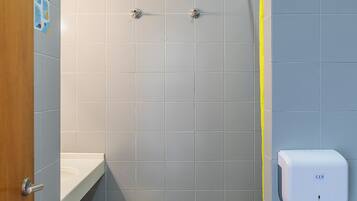 Un baño con ducha, secamanos y toallero.