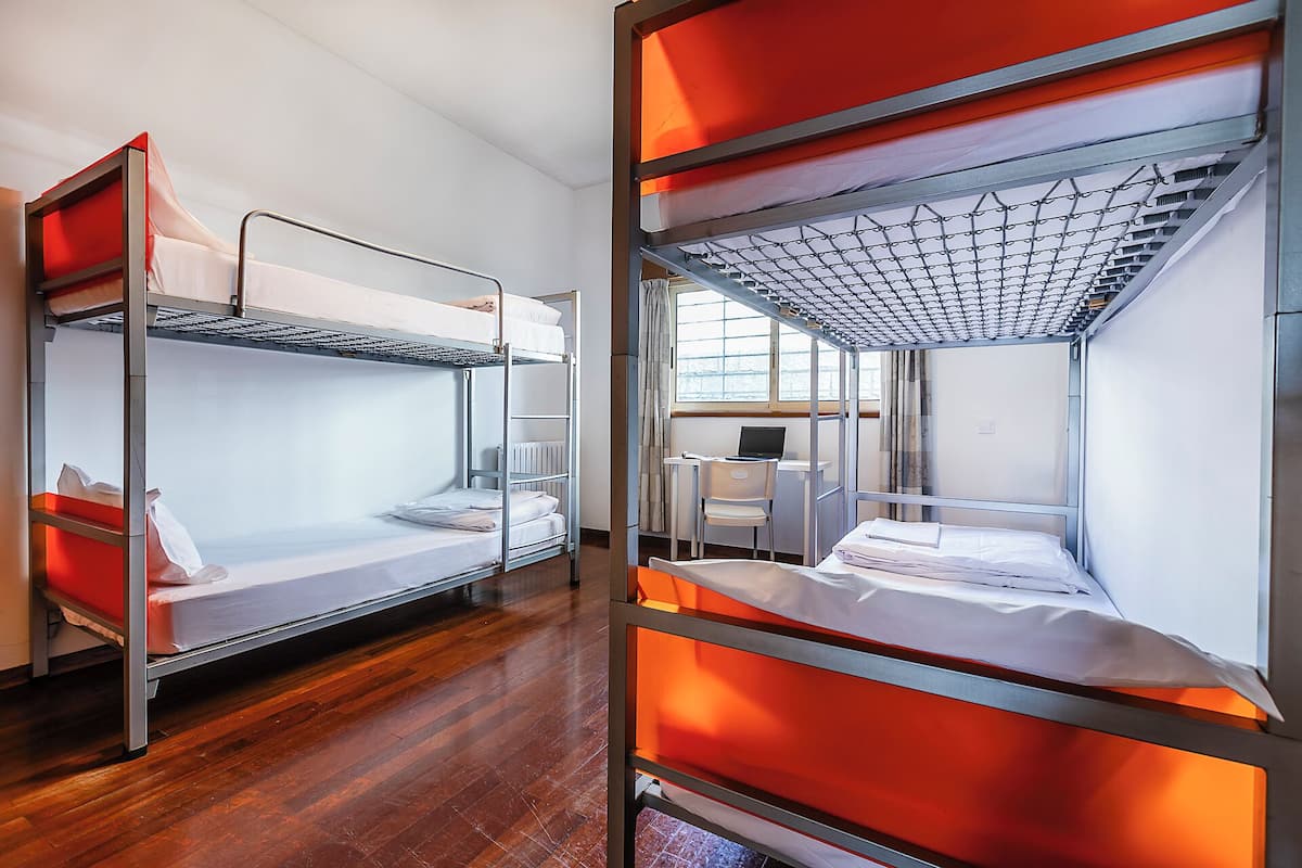 Une chambre d’étudiant avec des lits superposés, un bureau et une chaise.