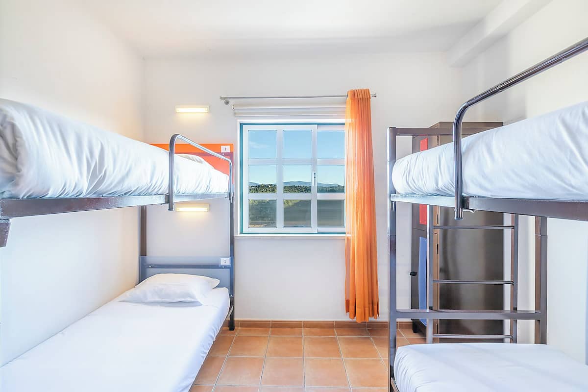 Un dormitorio con literas, una ventana con cortinas y vistas al exterior.