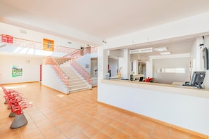 Un espace d’accueil comprenant un escalier, un comptoir de réception et un sol carrelé.
